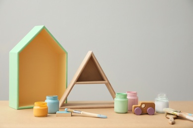 Photo of Composition with jars of paints and shelves on wooden table. Interior elements