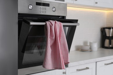 Photo of Clean checkered towel on oven door in kitchen