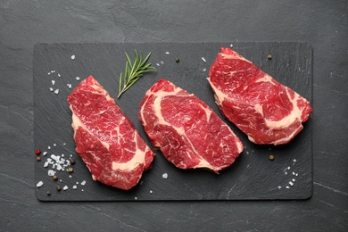 Fresh meat steaks on dark table, top view