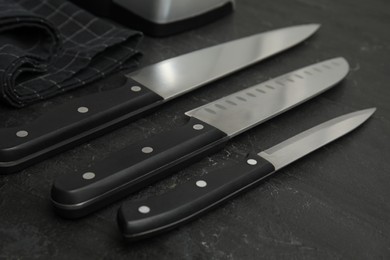 Photo of Set of sharp knives on black table, closeup