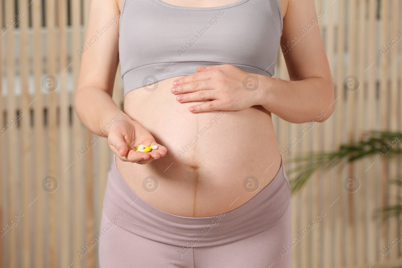 Photo of Pregnant woman taking pills indoors, closeup view
