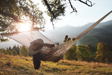 Young woman resting in hammock outdoors at sunset