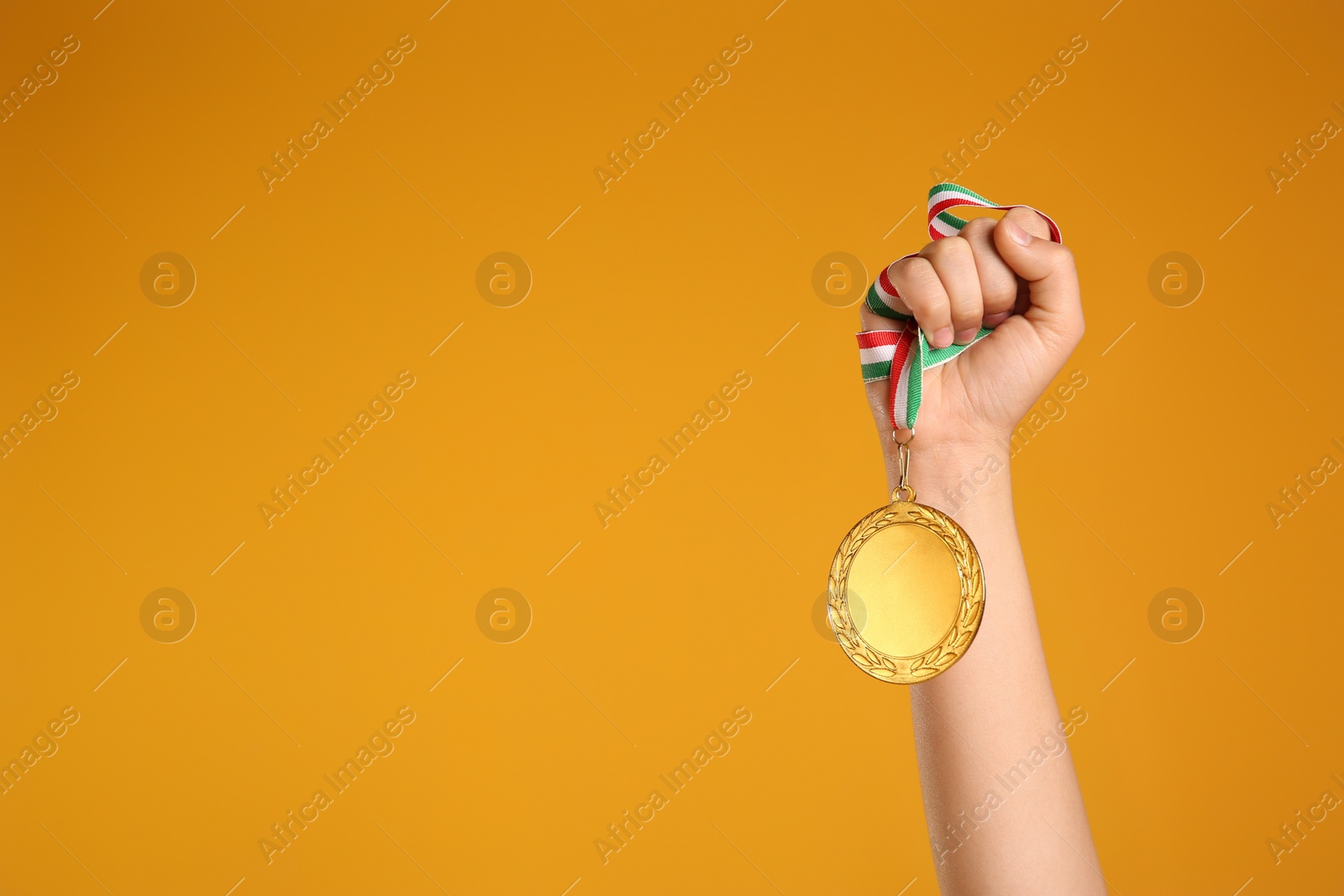 Photo of Woman holding gold medal on yellow background, closeup. Space for text