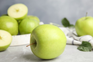 Fresh ripe green apples on grey stone table against blue background, space for text