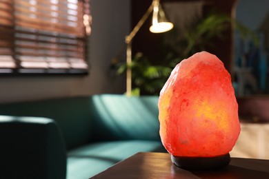 Himalayan salt lamp on wooden table indoors, space for text