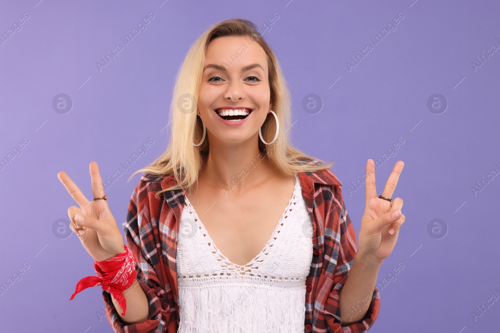 Photo of Portrait of happy hippie woman showing peace signs on purple background
