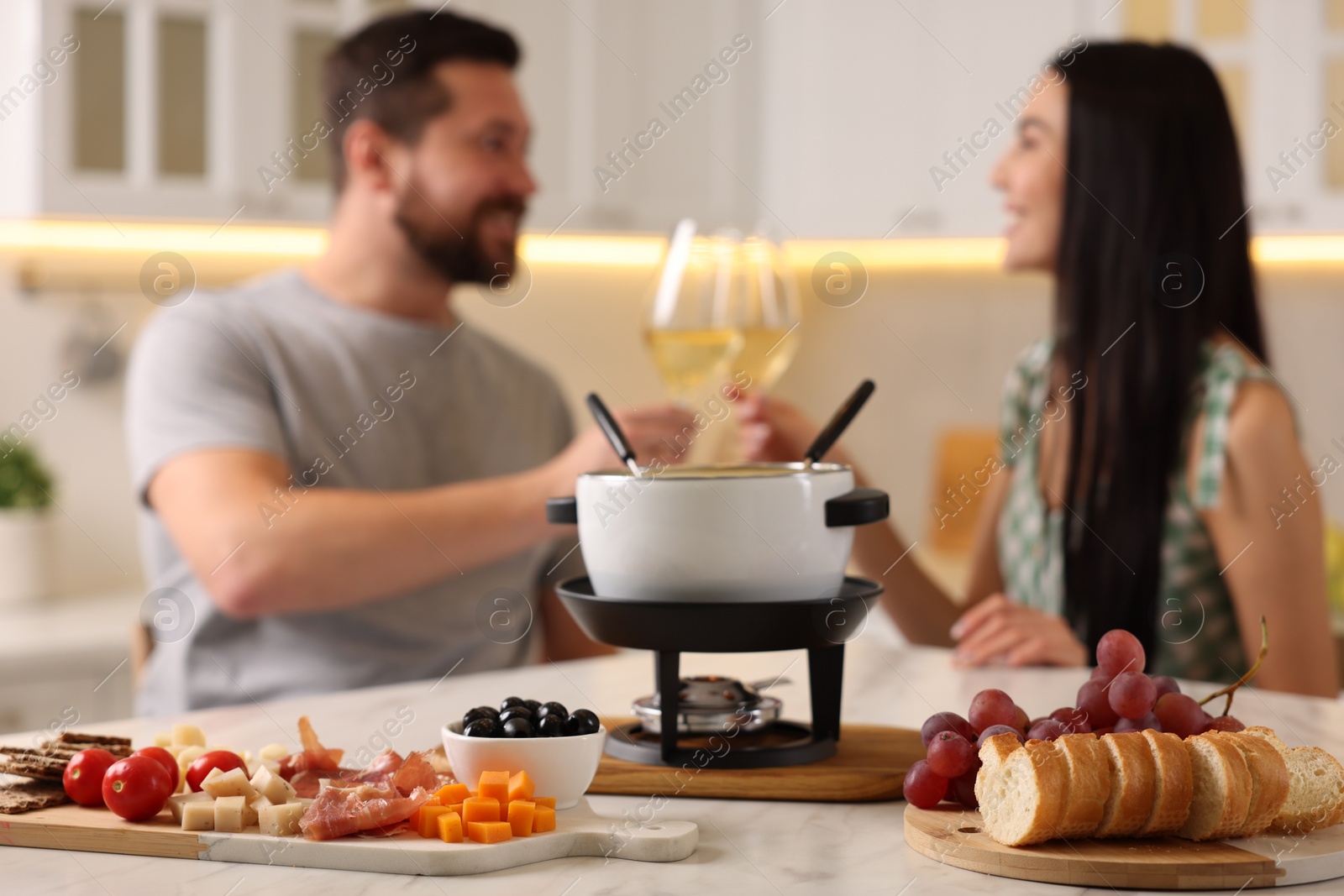 Photo of Couple spending time together during romantic date in kitchen, focus on fondue