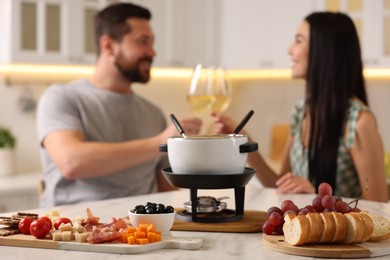 Photo of Couple spending time together during romantic date in kitchen, focus on fondue