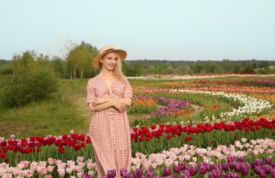 Happy woman in beautiful tulip field outdoors