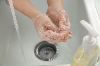 Photo of Woman washing hands with liquid soap, closeup