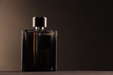 Photo of Luxury men`s perfume in bottle on table against dark background, space for text