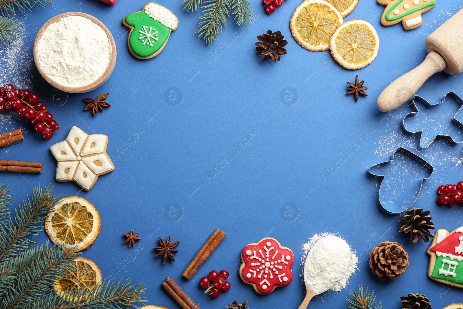 Photo of Frame of Christmas cookies, decor and flour on blue background, flat lay. Space for text