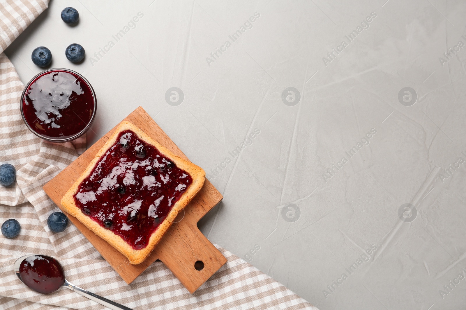 Photo of Toast with blueberry jam served on grey table, flat lay. Space for text