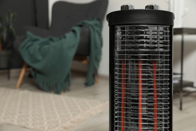Photo of Modern electric halogen heater in room, closeup. Space for text