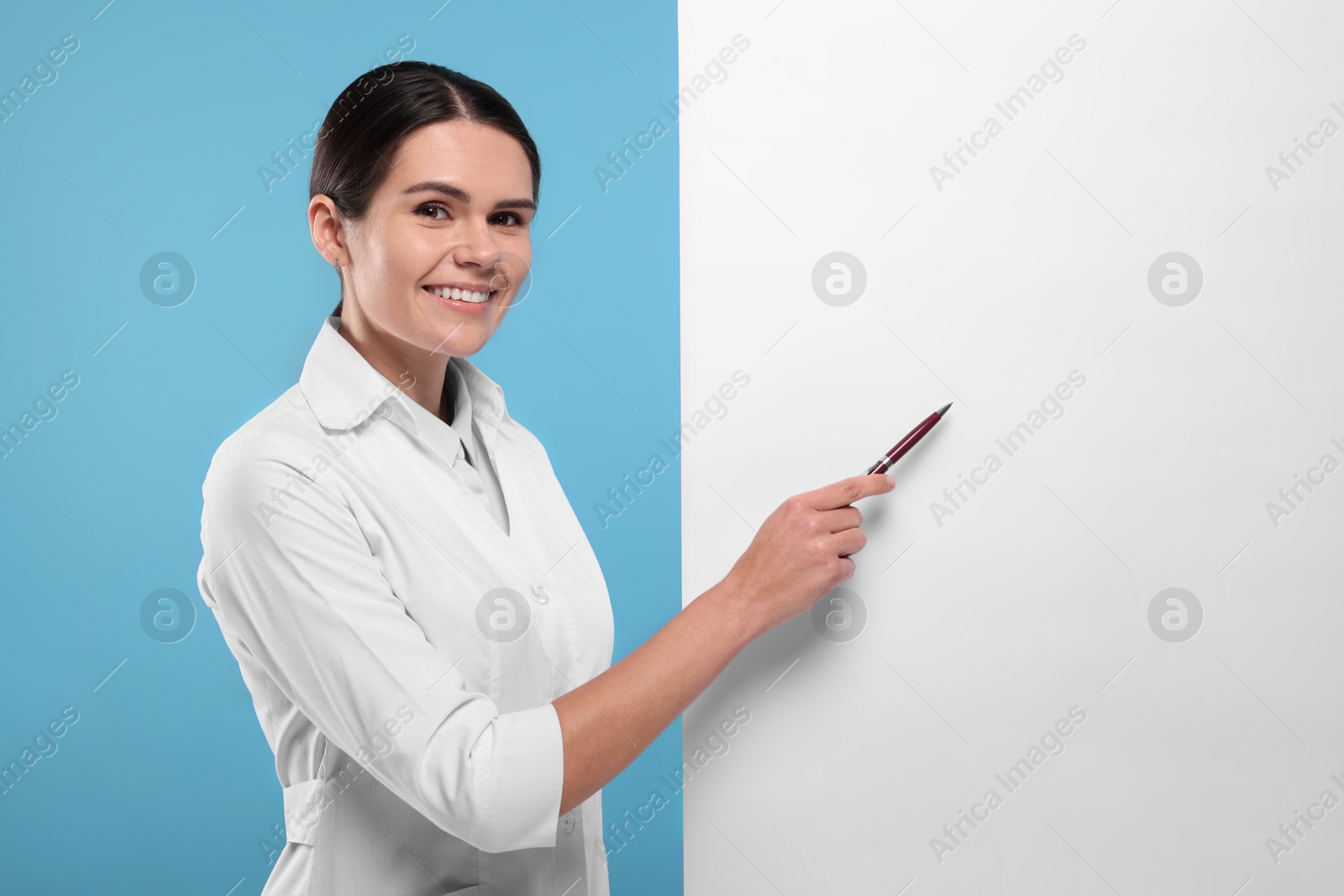 Photo of Ophthalmologist pointing at blank banner on light blue background, space for text