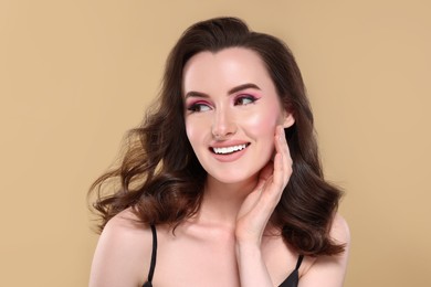 Photo of Portrait of beautiful young woman with makeup and gorgeous hair styling on beige background