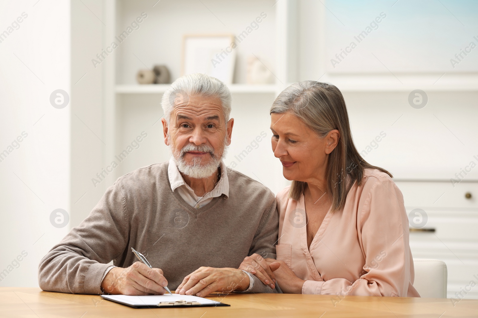 Photo of Senior couple signing Last Will and Testament indoors