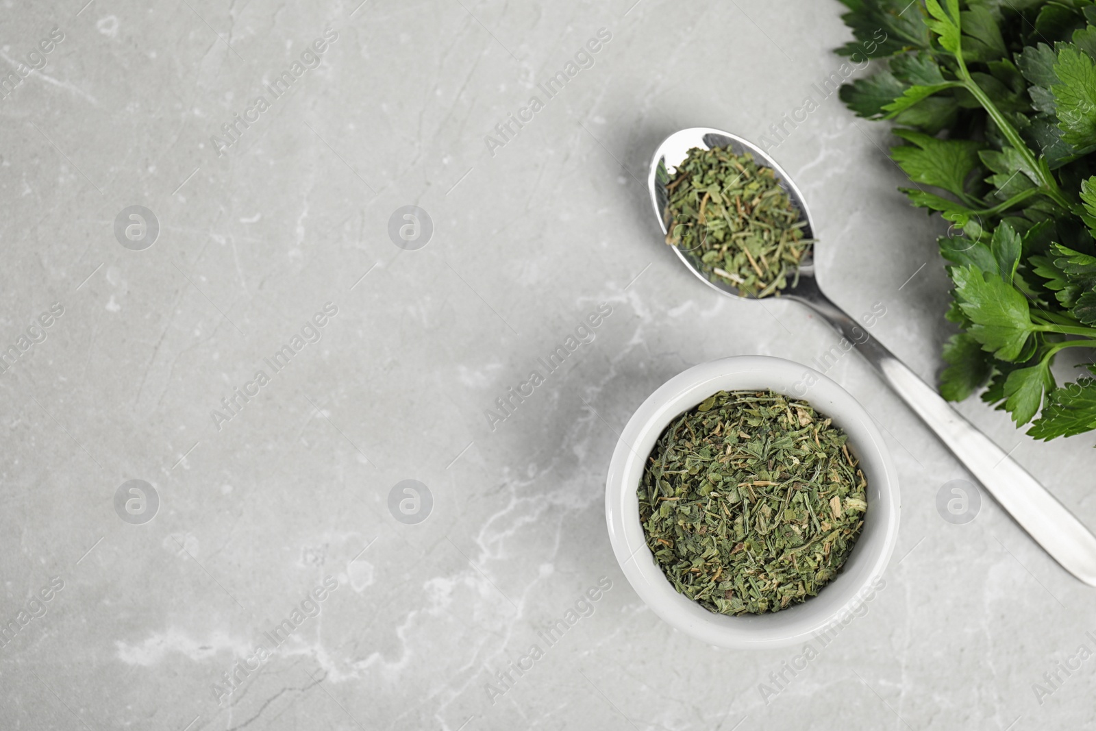 Photo of Flat lay composition with fresh and dried parsley on grey marble table. Space for text
