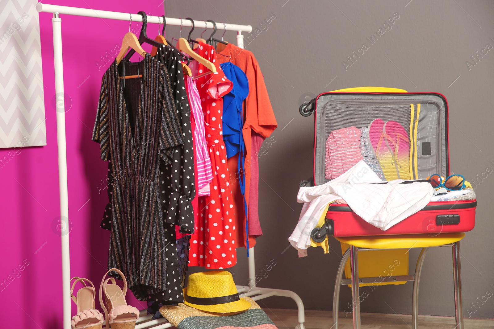 Photo of Open suitcase with different clothes and accessories for summer journey on chair