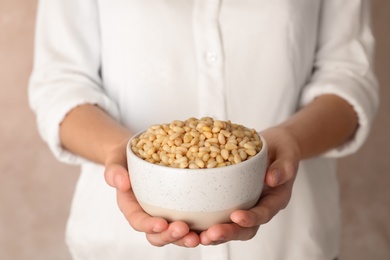 Photo of Woman holding bowl with shelled pine nuts, closeup