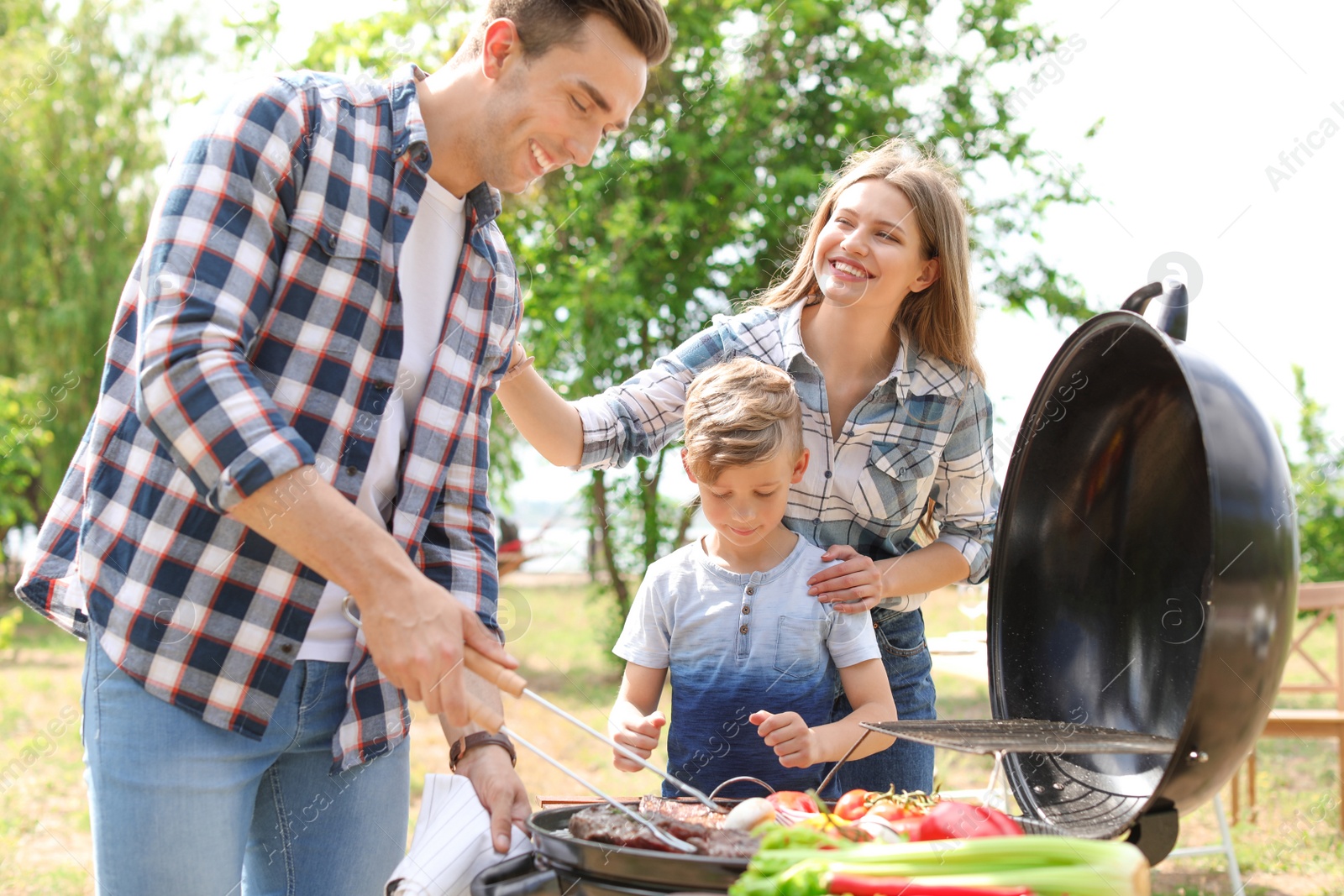 Photo of Happy family having barbecue with modern grill outdoors