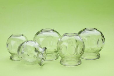 Photo of Glass cups on light green background. Cupping therapy