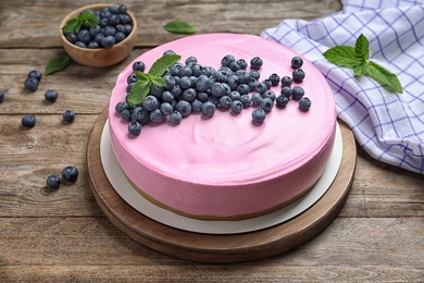 Photo of Board with tasty blueberry cake on wooden table