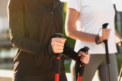 Photo of Women practicing Nordic walking with poles outdoors on sunny day, closeup