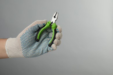 Photo of Man with combination pliers on grey background, closeup. Space for text