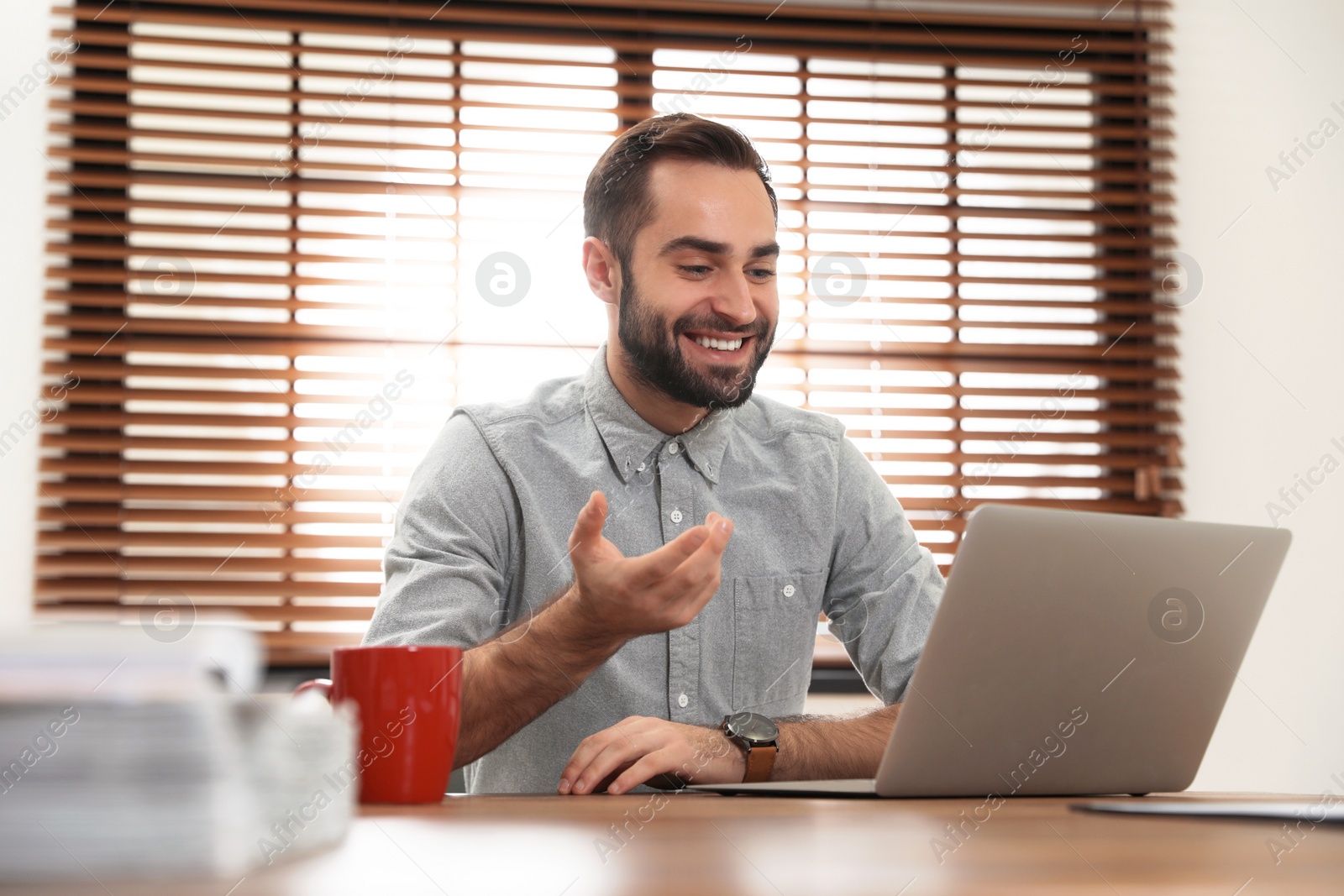 Photo of Man using video chat on laptop in home office