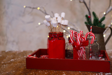 Photo of Marshmallow and candy canes in wooden tray. Christmas celebration