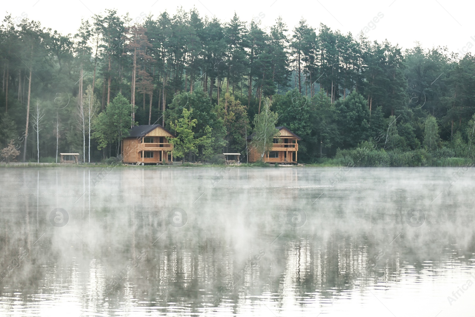 Photo of Beautiful landscape with forest and houses near lake. Camping season