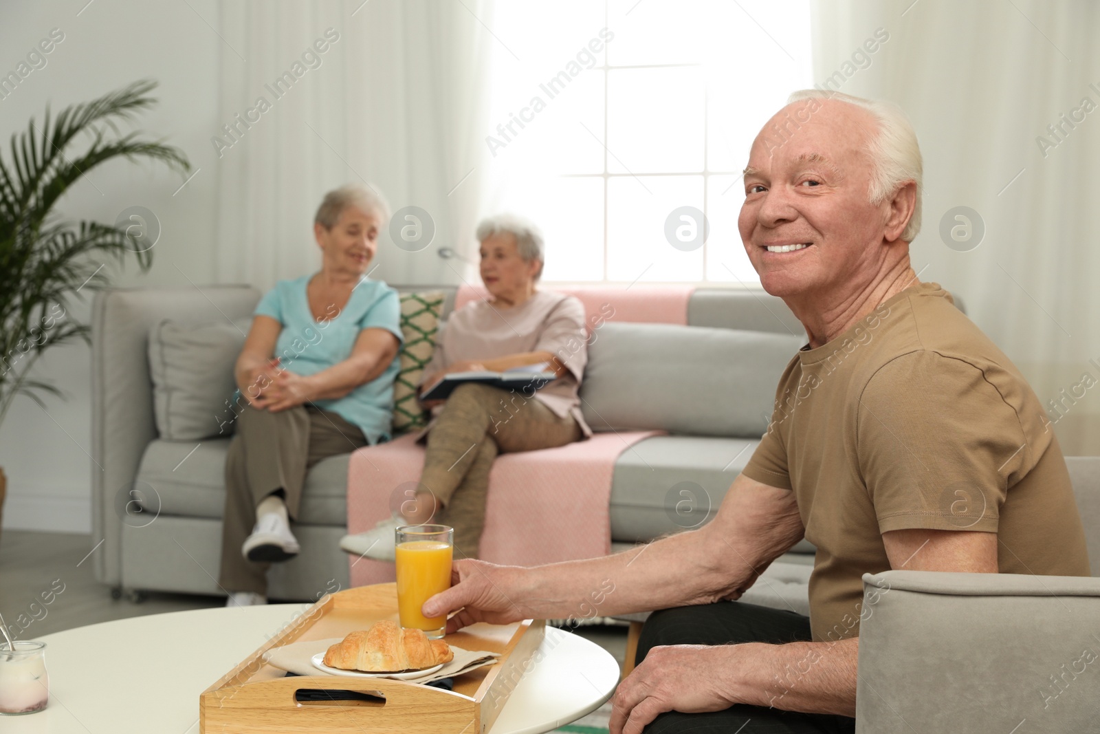 Photo of Elderly man having breakfast at nursing home, space for text. Assisting senior people