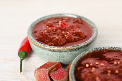 Photo of Tasty rhubarb sauce and ingredients on white wooden table, closeup