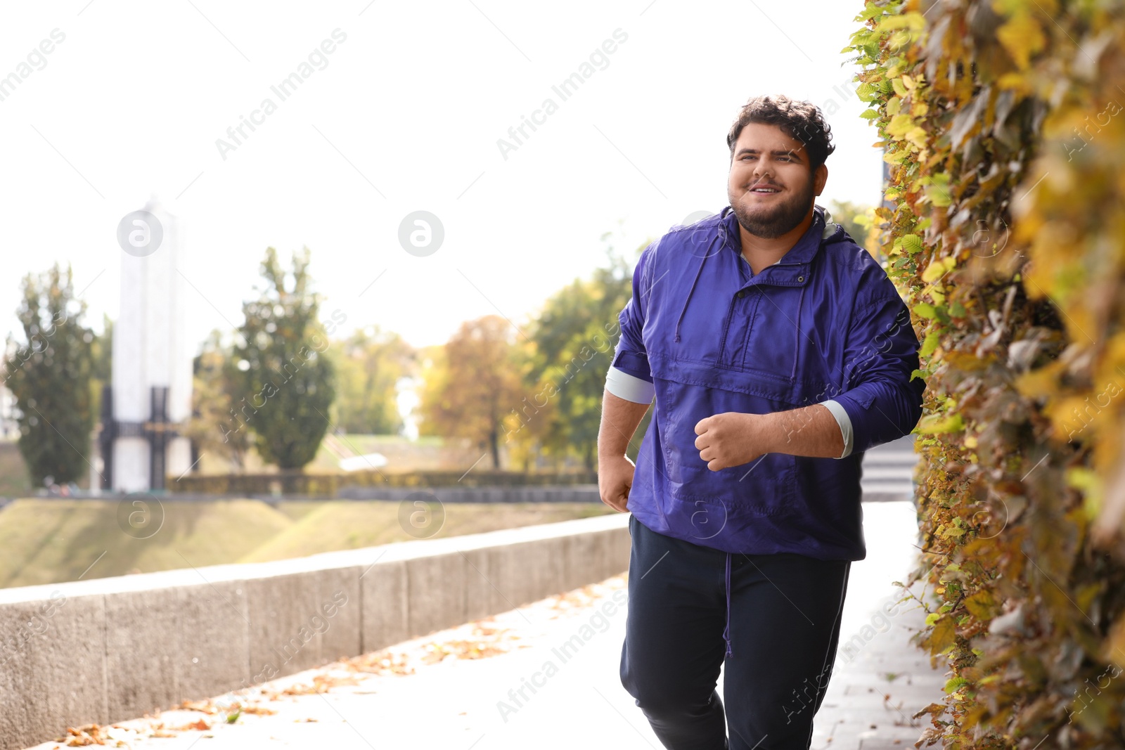 Photo of Young overweight man running in park. Fitness lifestyle