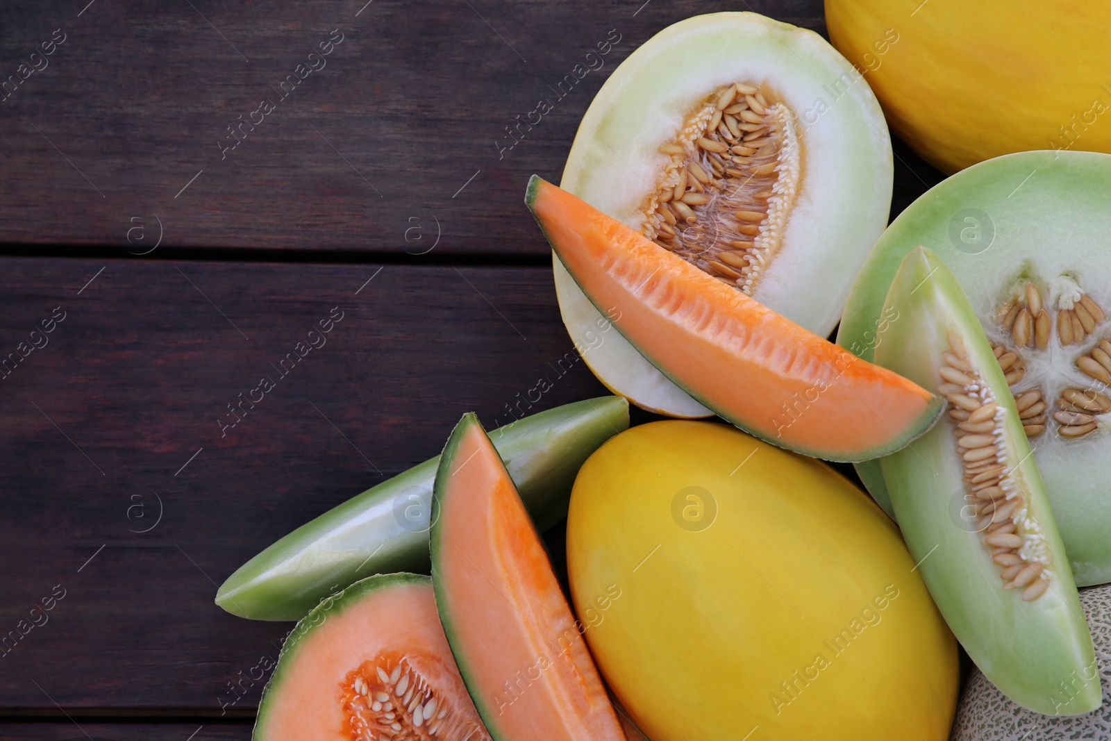 Photo of Different types of tasty ripe melons on wooden table, flat lay. Space for text