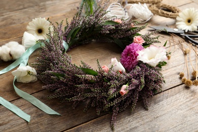 Photo of Beautiful autumnal wreath with heather flowers on wooden table