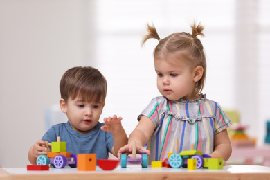 Cute little children playing with toys at table