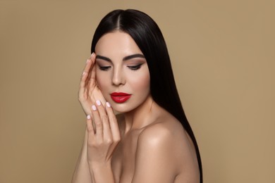 Portrait of young woman wearing beautiful red lipstick on beige background