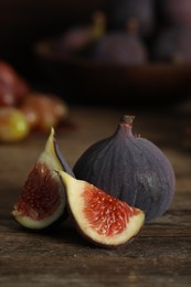 Photo of Whole and cut tasty fresh figs on wooden table, closeup