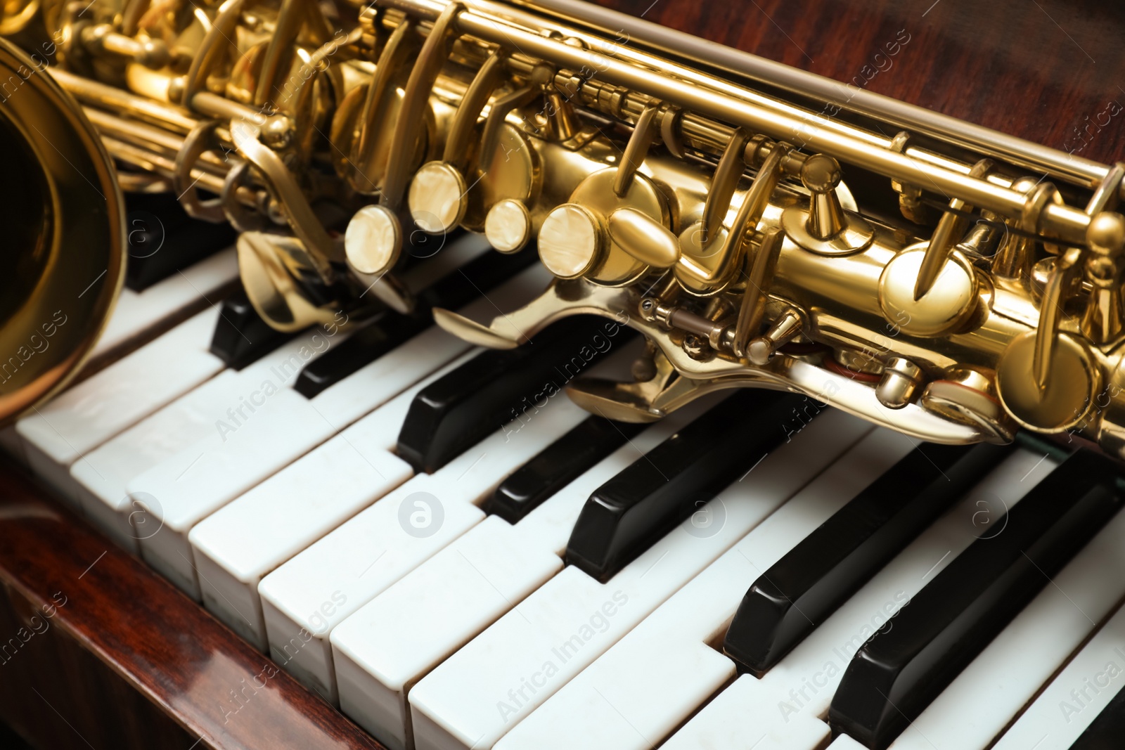 Photo of Beautiful saxophone on piano keys, closeup. Musical instruments