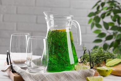 Photo of Jug of homemade refreshing tarragon drink and glasses on table