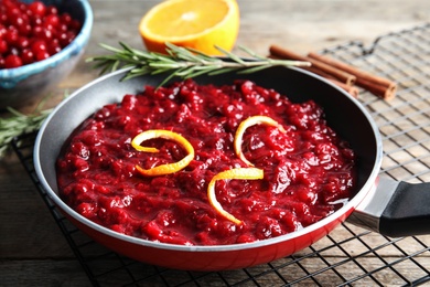 Photo of Tasty cranberry sauce with citrus zest in pan on table