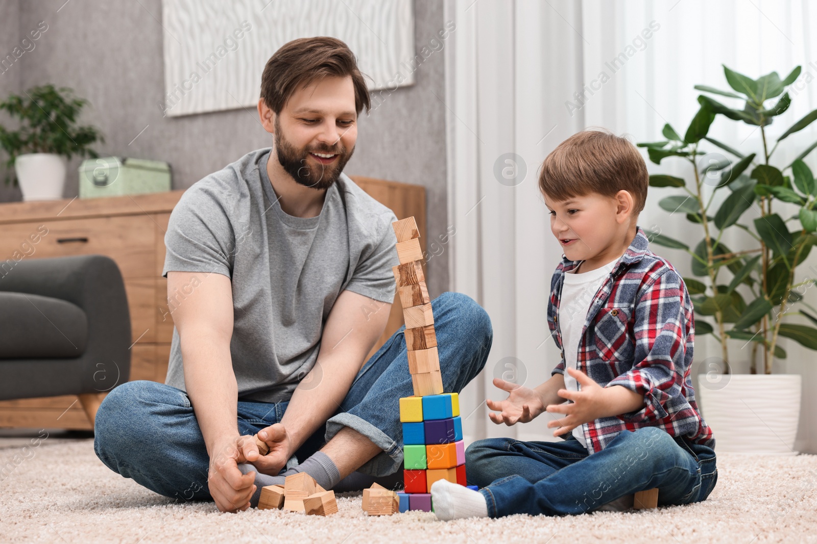 Photo of Happy dad and son building tower with cubes at home