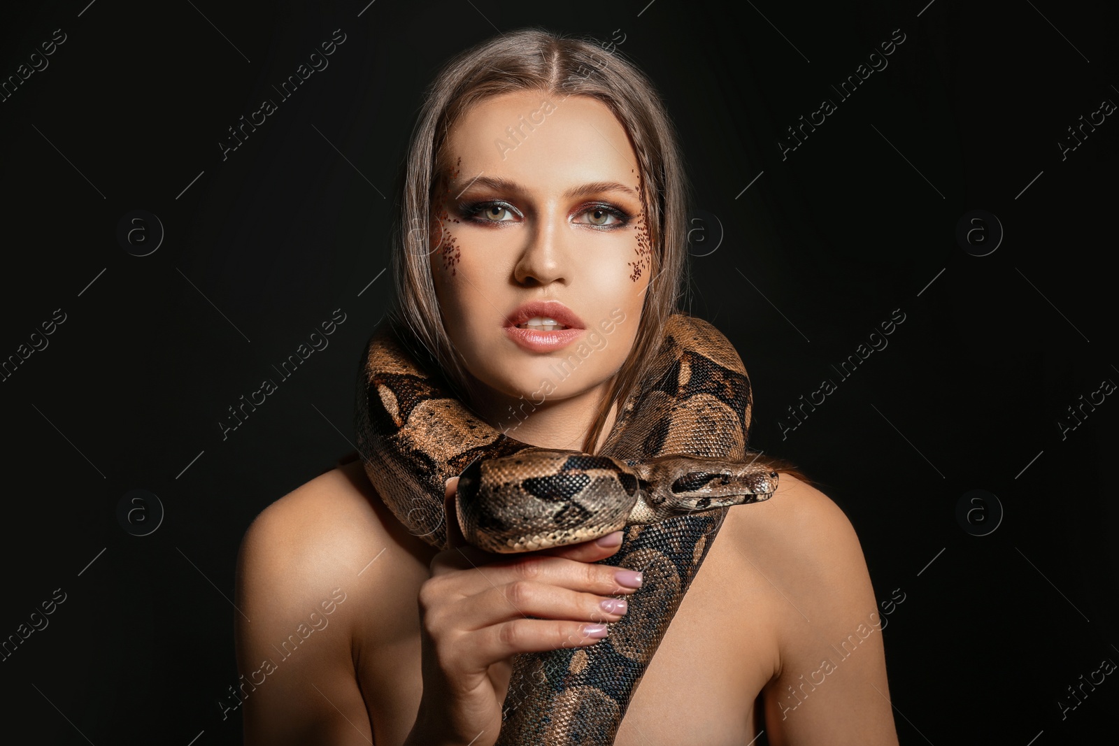 Photo of Beautiful woman with boa constrictor on black background