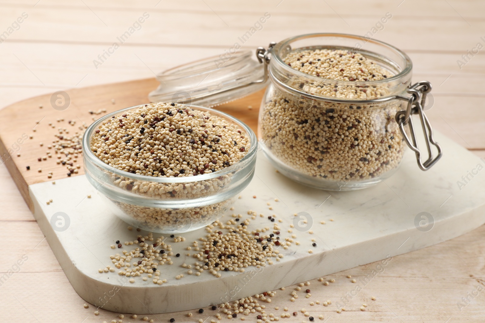 Photo of Bowl and jar with raw quinoa seeds on wooden table