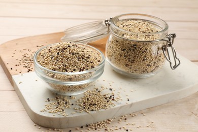 Photo of Bowl and jar with raw quinoa seeds on wooden table