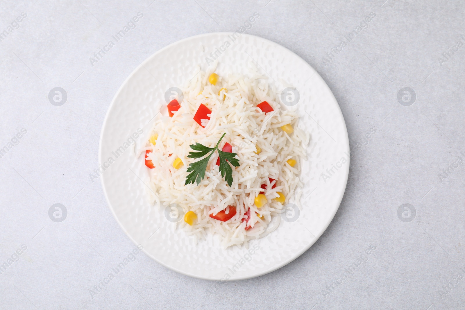 Photo of Delicious rice with vegetables and parsley on light gray table, top view