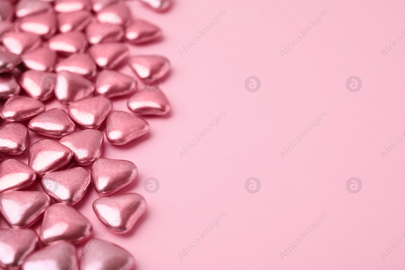 Photo of Many delicious heart shaped candies on pink background. Space for text