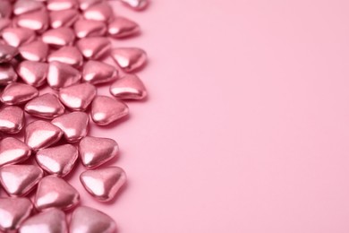 Many delicious heart shaped candies on pink background. Space for text